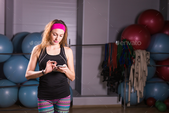 Happy young woman using activity tracker in fitness gym