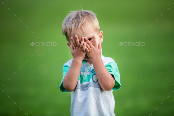 Little boy playing peek-a-boo outdoors