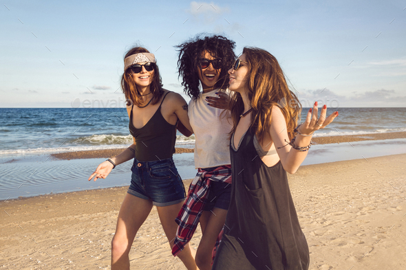 Three friends walking on the beach and laughing