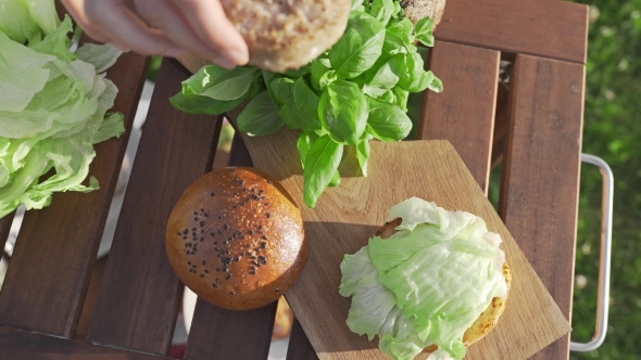 VideoHive The Cook Puts Cutlet To the Bun and Makes Burger Outside Countryside Cooking Open Air Cooking 20314843 VideoHive The Cook Puts Cutlet To the Bun and Makes Burger Outside Countryside Cooking Open Air Cooking 20314843