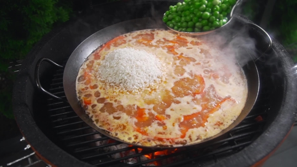 VideoHive The Cook Makes Paella on the Open Fire and Adds Green Pea To the Other Ingredients in the Big Hot 20320851 VideoHive The Cook Makes Paella on the Open Fire and Adds Green Pea To the Other Ingredients in the Big Hot 20320851