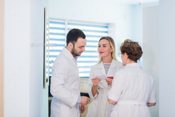 Mature doctor discussing with nurses in a hallway hospital. Doctor discussing patient case status - Stock Photo - Images