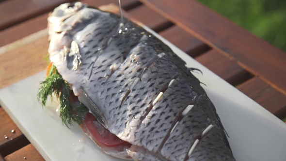 Raw Carp Is Prinkling with Olive Oil for Being Grilled, Preparations for the Barbecue, Cooking Fish alt
