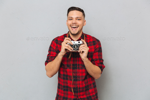 Happy Man in shirt making photo on retro camera