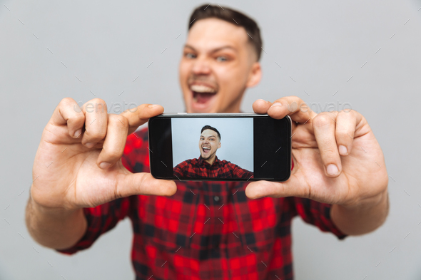 Close up image of happy man making photo on smartphone