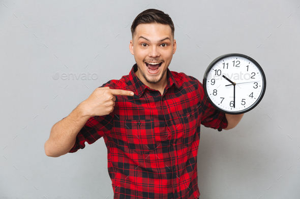 Happy man holding clock and pointing at their