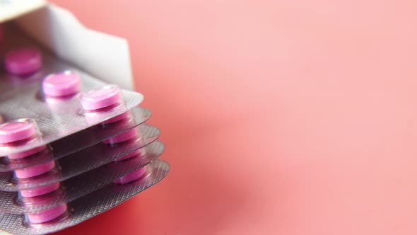 Close Up of Pills of Blister Pack in a Packet on Pink Background alt