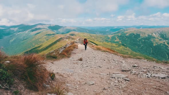 Tourist with a Backpack Climbing Up Along the Stone Mountain Trail on the Hill alt