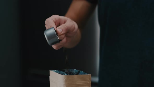 Closeup of Barista hand putting beans in a craft bag in cafe it slow motion closeup with 4k. alt
