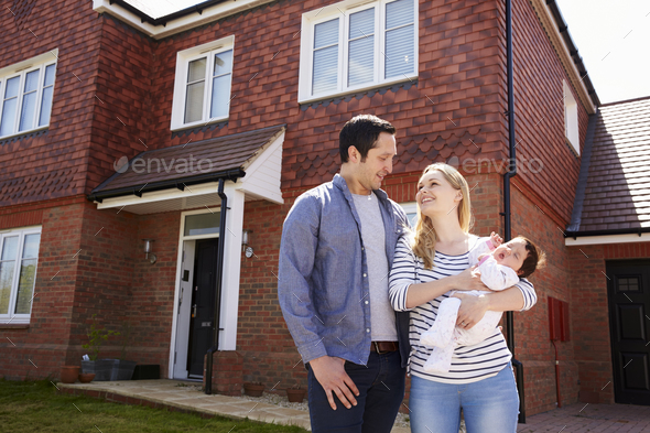 Young Family Standing Outside New Home