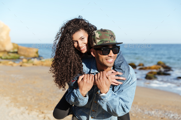 Happy african loving couple walking outdoors at beach