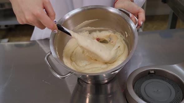 Closeup of a Girl Cook Mixing Dough with a Silicone Spatula in a Metal Bowl alt