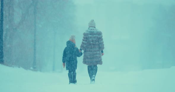 Woman with a Child Go in the Winter in Heavy Snow alt