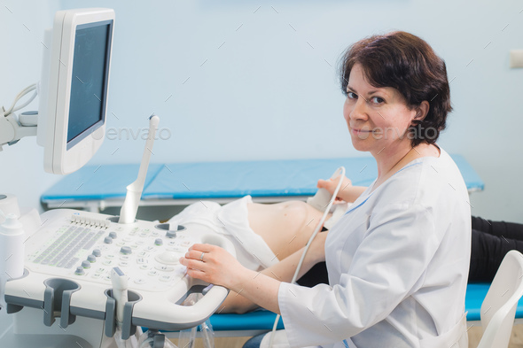 Close up of incognito doctor using ultrasound equipment for screening pregnant woman and press on - Stock Photo - Images