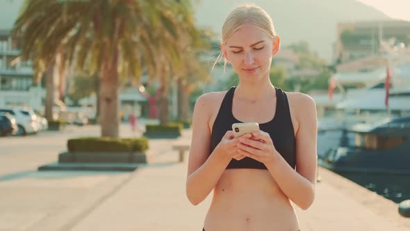 Attractive Fitness Woman Chatting on Smartphone During Sport Break Outdoor