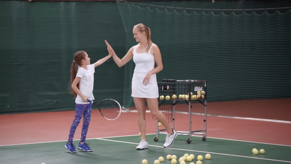 Trainer Woman Giving High Five To Little Girl on Tennis Court alt