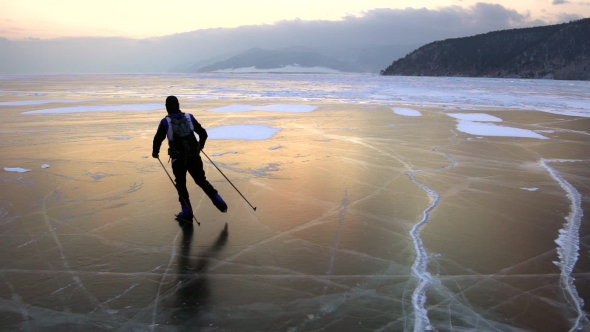 Man Are Skating on the Ice of Frozen Lake Baikal During Beautiful Sunset.