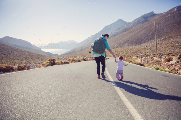 Young woman and little daughter walking down road