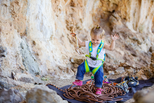 Happy little girl playing with rock climbing gear
