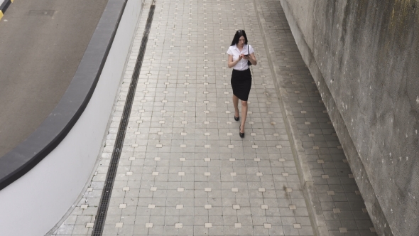 Business Woman Walking and Using a Smartphone