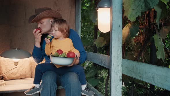 Father and Small Child Eat Fresh Organic Vegetables From Farm Sitting on Porch