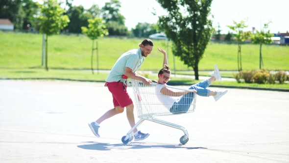 A Young Couple Is Fooling Around in a Parking Lot Near a Supermarket alt