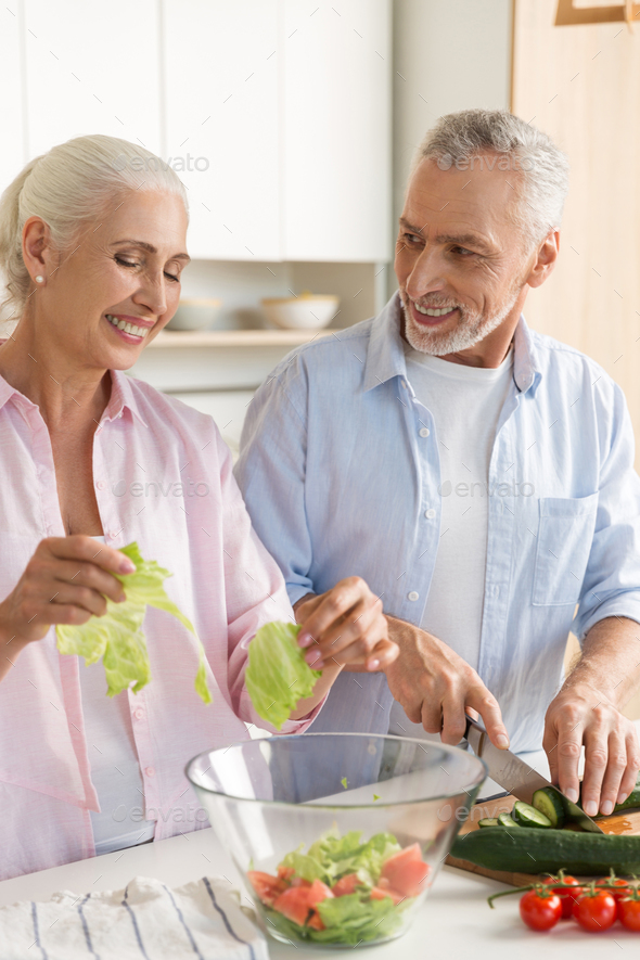 Happy mature loving couple family cooking salad