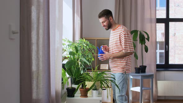 Happy Smiling Man Watering Flowers at Home alt