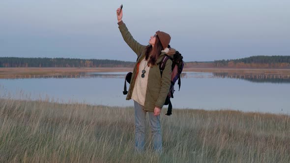 Young Woman in the Forest Trying To Catch a Mobile Signal. alt