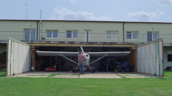 Aviator Fixing Airplane Propeller Inside Repair Hangar on Countryside Aerodrome alt