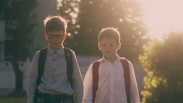 Boys with Backpacks Walk After Lessons in Park Slow Motion alt