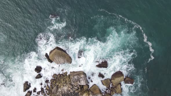 Top down aerial view of giant ocean waves crashing and foaming in coral beach alt