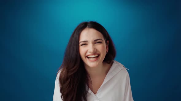 Cheerful Young Woman Smiling and Laughing Against Blue Background