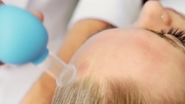 Beautician cosmetologist makes face vacuum massage with cupping cup alt