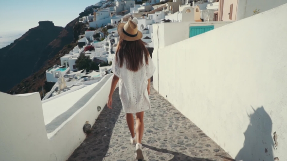 Young Sexy Woman Is on the Greek Island Santorini in a White Dress and and Straw Hat White Greek