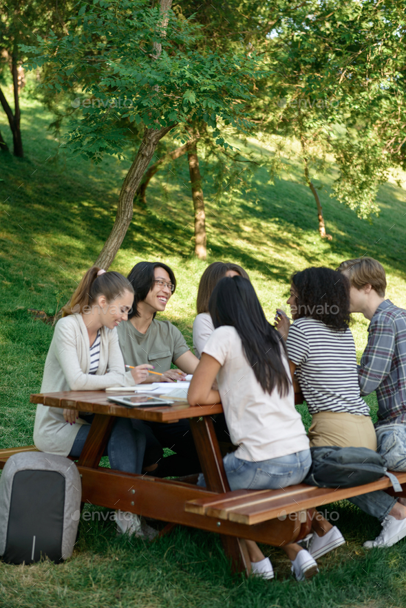 Young students sitting and studying outdoors while talking.