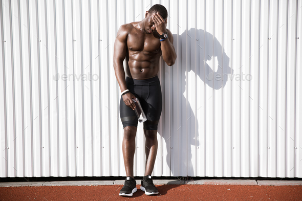 Midsection Of Man Holding Water Bottle While Standing Against Wall stock  photo