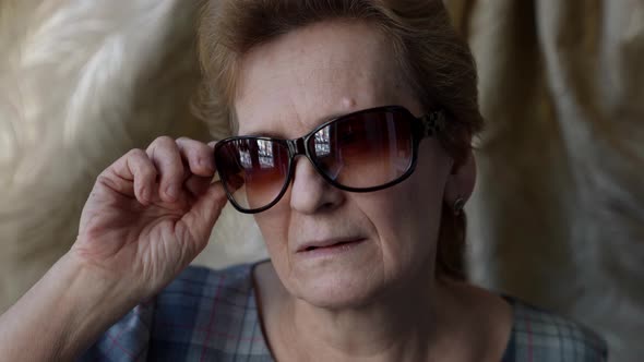 Retiree Woman is Putting on and Off Sunglasses Protection for Eyes in Sunny Day alt