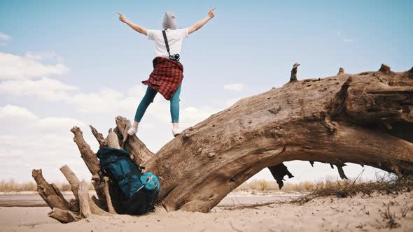 Happy Young Woman Standing on the Tree Trunk on the Sandy Beach with Outstretched Hands. Backpacker alt
