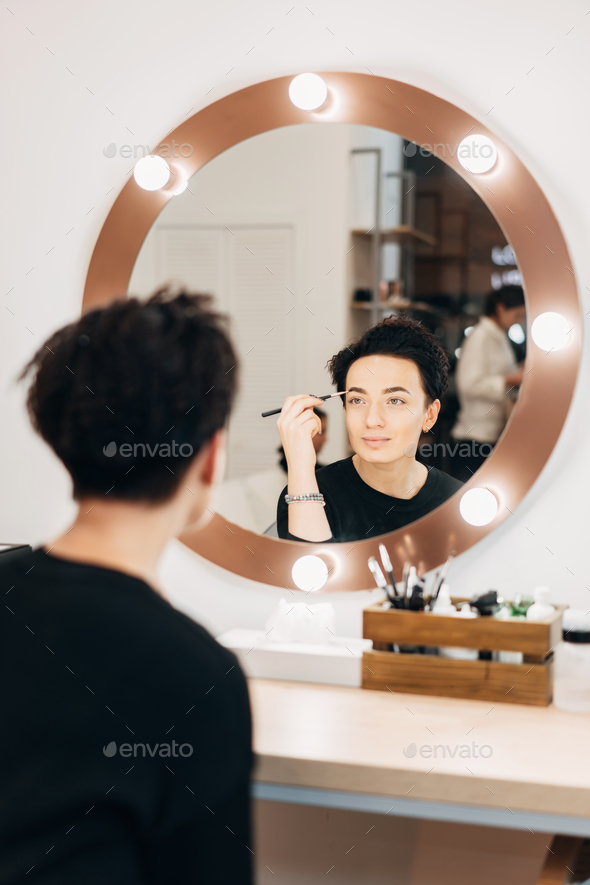 Attractive woman at the mirror in beauty studio - Stock Photo - Images