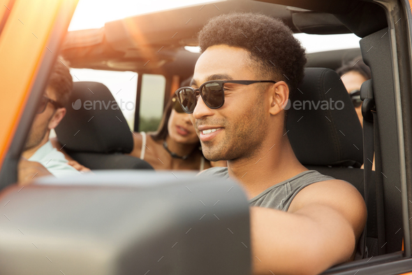 Smiling young african man driving a car