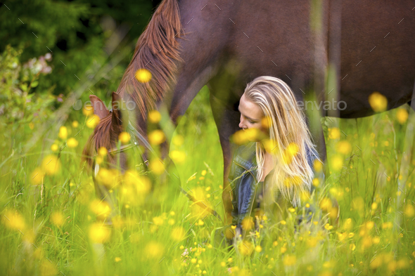 Smiling woman sits in the meadow with her arabian horse - Stock Photo - Images