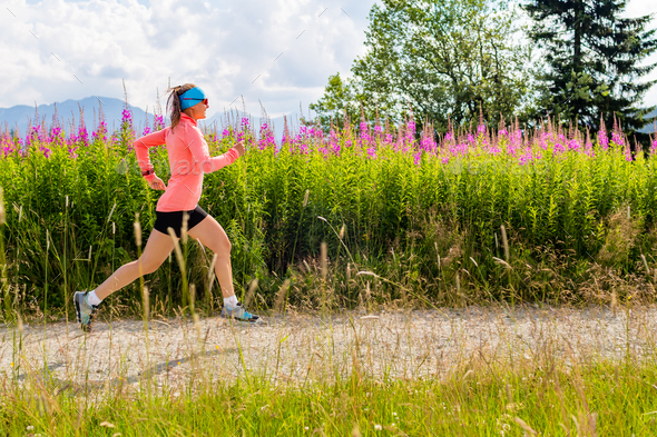 Young woman running on country road in mountains, summer day Stock ...
