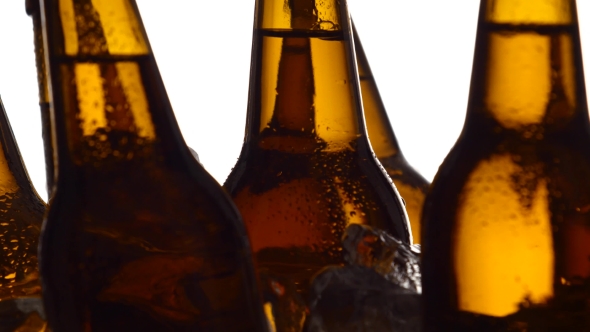 Few Bottles of Dark Beer in Pieces of Ice. White Background. Silhouette. alt