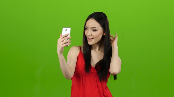 Asian Girl Does Selfie, She Smiles While Looking at the Camera. Green Screen alt