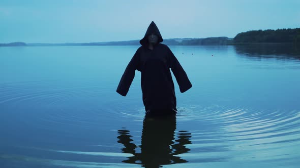 Dark ghost in black cloak with hood among nature alt