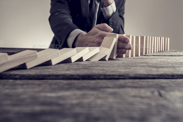 Toned image of a businessman stopping domino effect - Stock Photo - Images