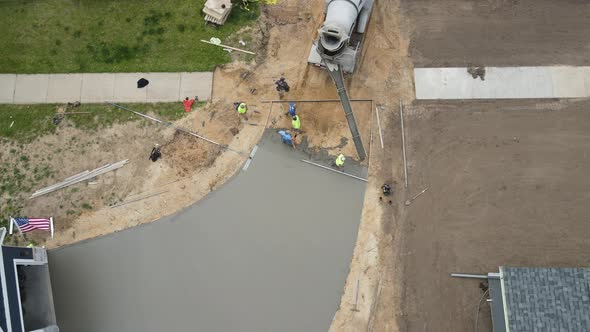 Birds eye view of concrete being poured to complete new driveway. Gravel and dirt base layers.