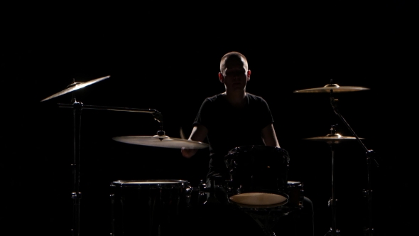 Musician Plays Professionally Good Music on Drums Using Sticks. Black Background. Silhouette alt