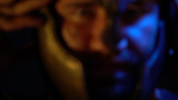 Focus on a Bearded Roman Warrior with a Scar on His Face That Puts a Helmet on His Head alt